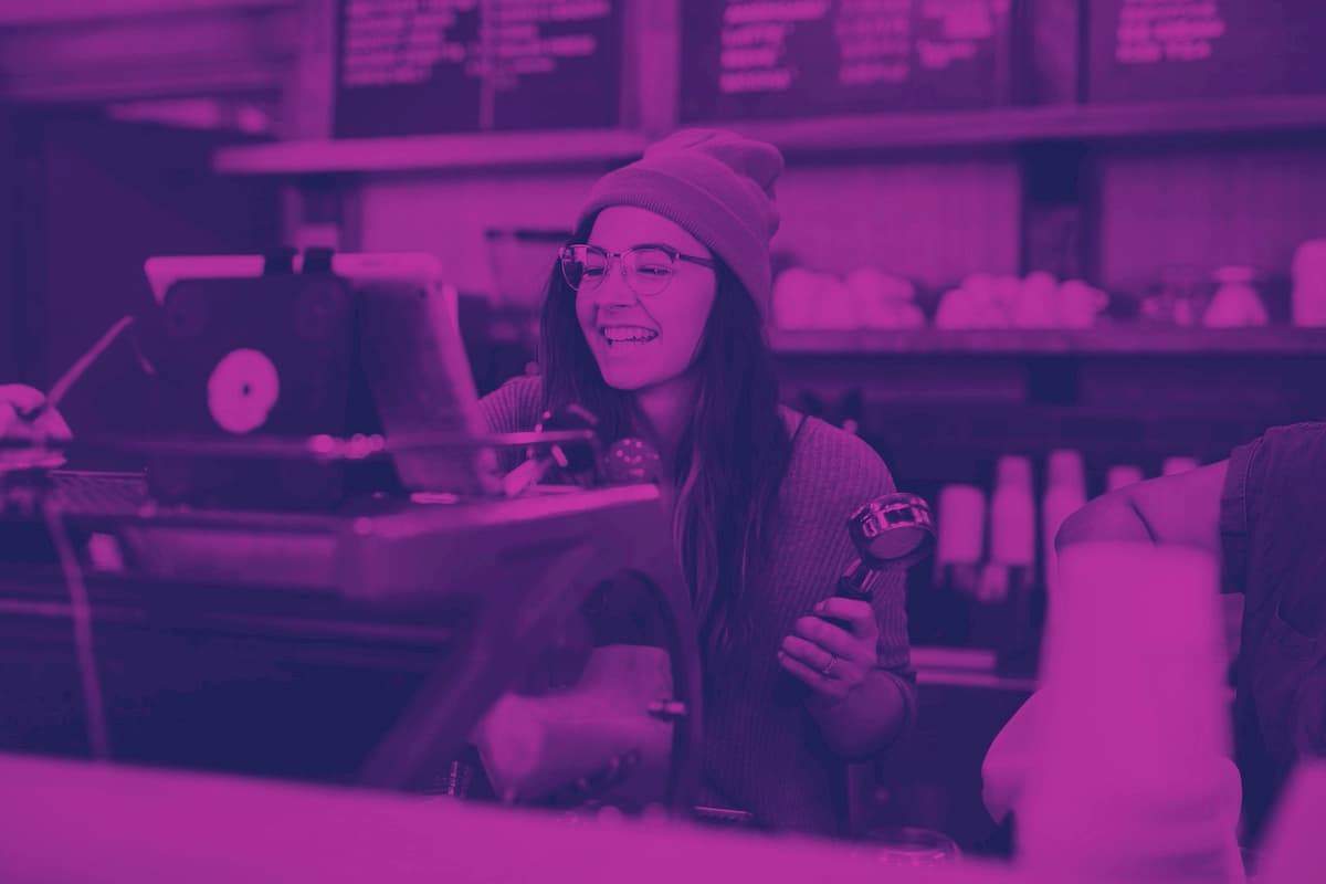 from-scratch-communications_are-customer-care-and-sales-the-same A barista brewing coffee with a brad smile on her face