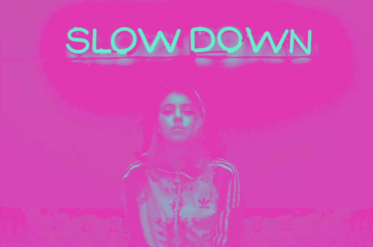 from-scratch-communications-win-the-content-race a woman in a training jacket under a neon sign saying 'slow down'