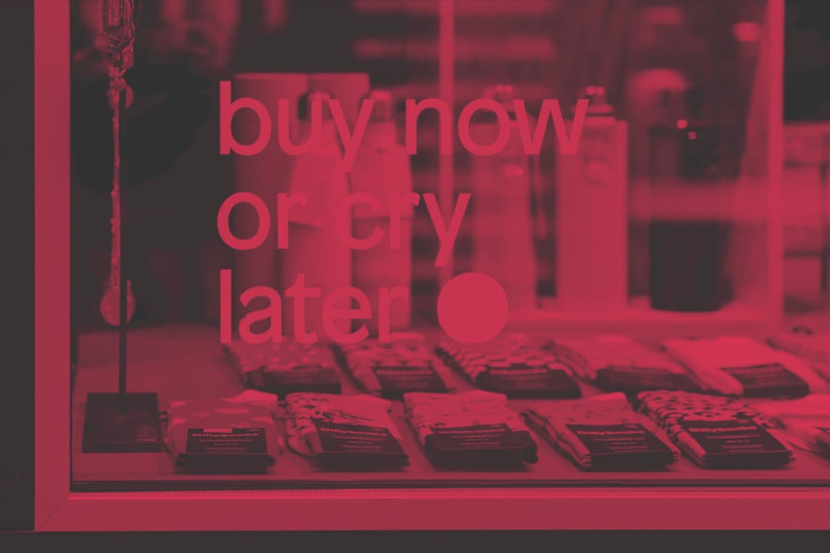 from-scratch-communications_web-audit-product-pages-that-convert a shop window in red/grey duotone. The window sticker says 'buy now or cry later'.