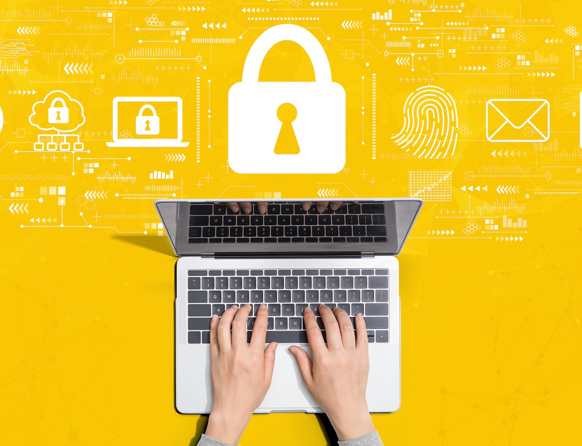 Someone is working on a laptop, only their hands are shown. The background is yellow with many different icons related to data security, such as padlocks, fingerprints, envelopes and more.