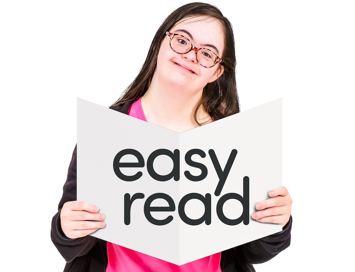 A woman with Down syndrome holds a brochure saying 'easy read'.